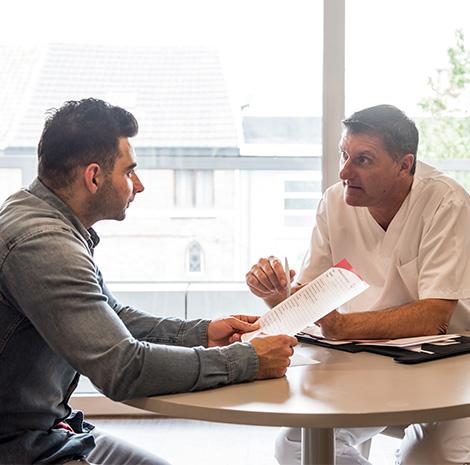 Verzorgende Mohammed praat met een man in een witte jas 