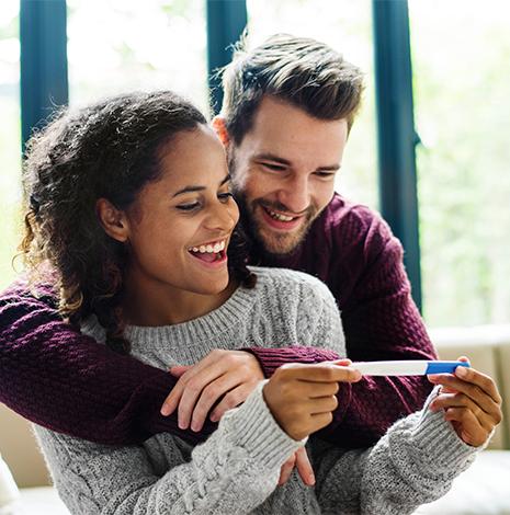 man en vrouw bekijken lachend een zwangerschapstest 