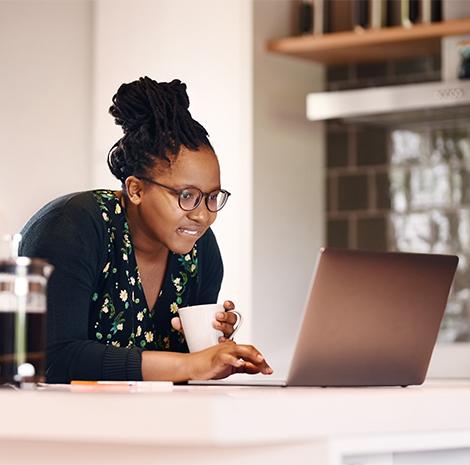 vrouw kijkt lachend naar een laptopscherm 