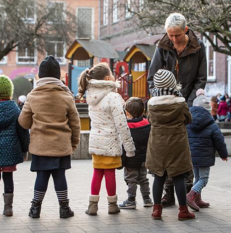 kleuterjuf Sofie is omringd door kleuters op de speelplaats 