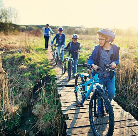 kinderen lopen op een houten paadje met de fiets aan de hand