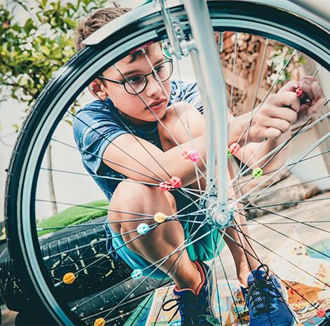 jongen bevestigt kleurrijke bolletjes aan de spaken van zijn fiets 