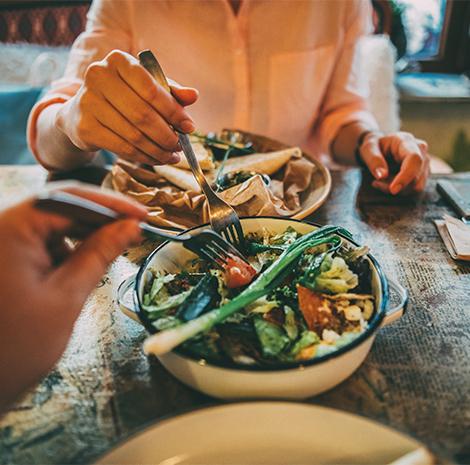 2 mensen eten met een vork van dezelfde kom salade