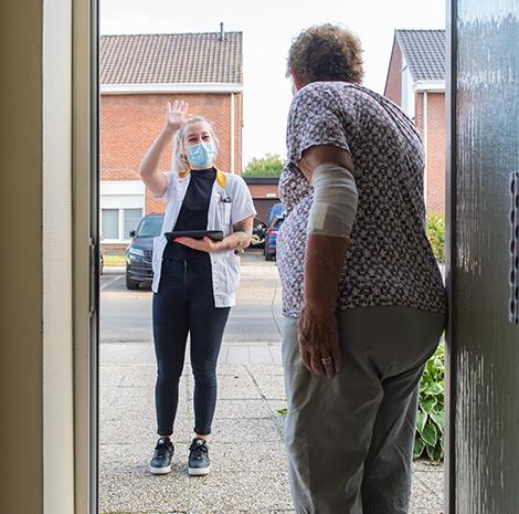 Palliatief verpleegkundige met patiënt aan deur