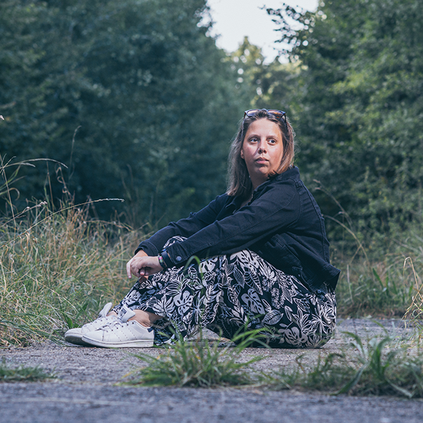 Vrouw zit neer en kijkt in de cameralens