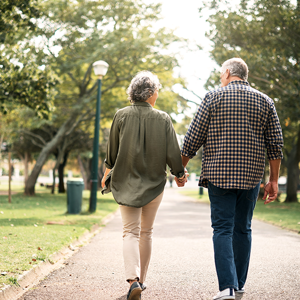 Afbeelding van man en vrouw die hand in hand aan het wandelen zijn in een park