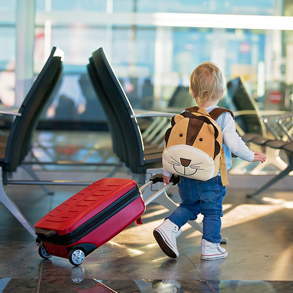 Afbeelding van kindje met koffer en rugzak op de luchthaven