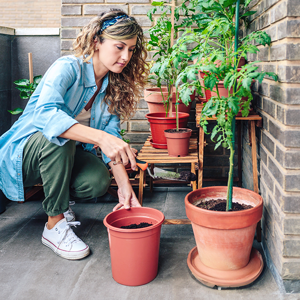 Vrouw plant groenten in bloempotten op haar balkon