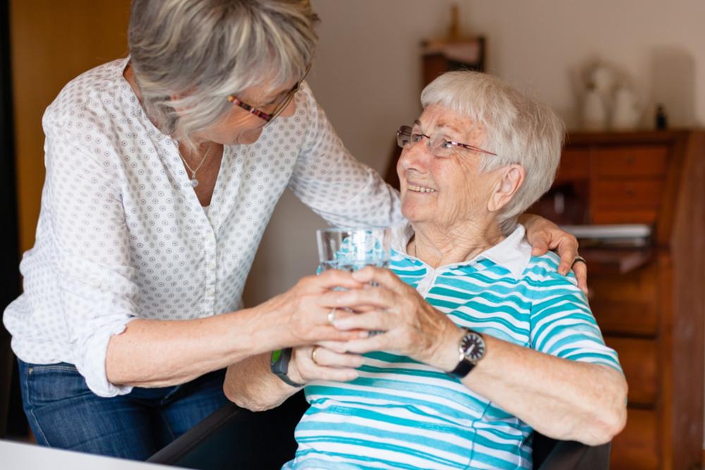 oudere vrouw krijgt water tijdens hittegolf
